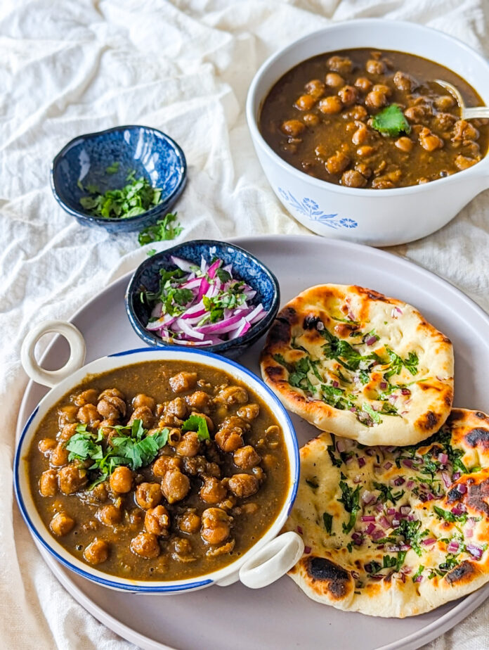 Pindi Chole served on a bowl along with warm pillowy kulchas and raw onion on the side